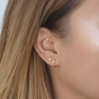 Close-up on woman's ear featuring Rose Gold Pave Bead Huggie Earrings CZ Crystal and stud. 