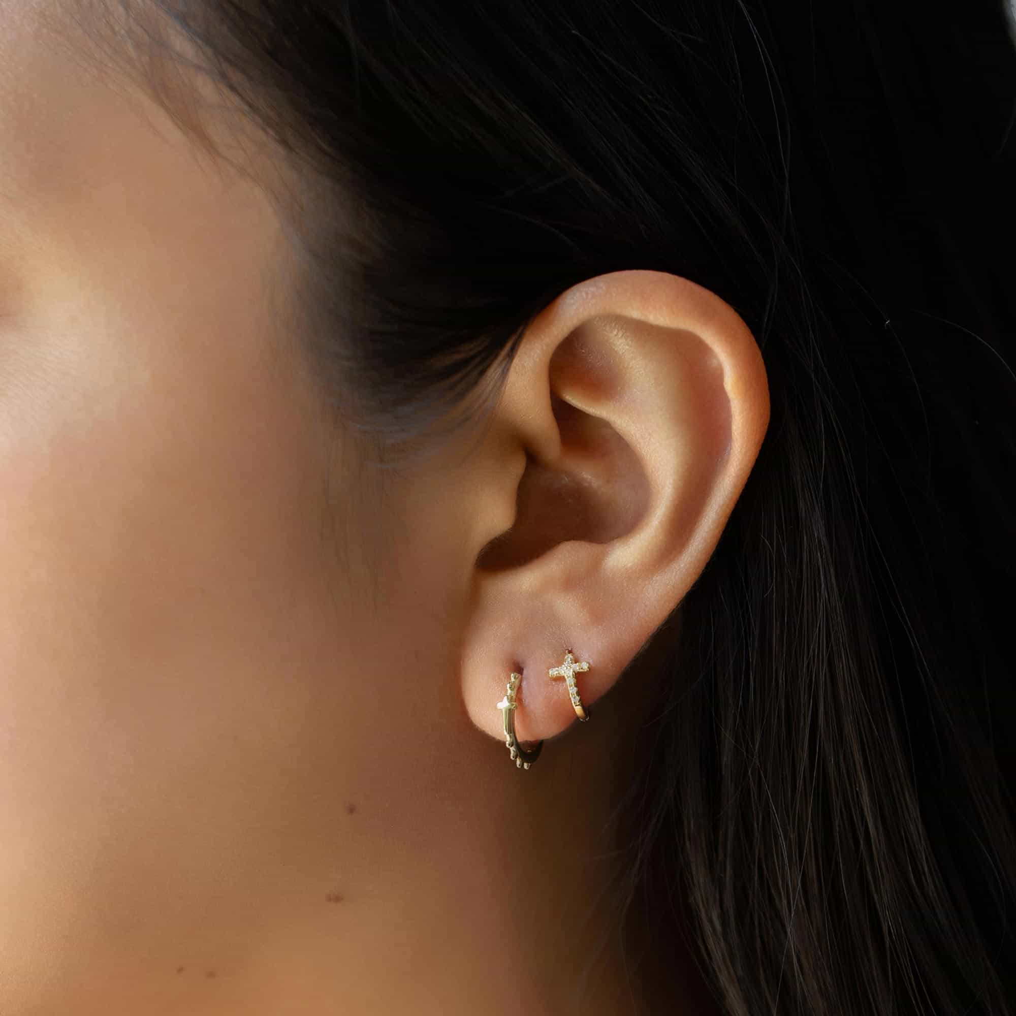 Close-up of a women with gold vermeil tiny cross earrings and cross bead mini hoop earrings. 