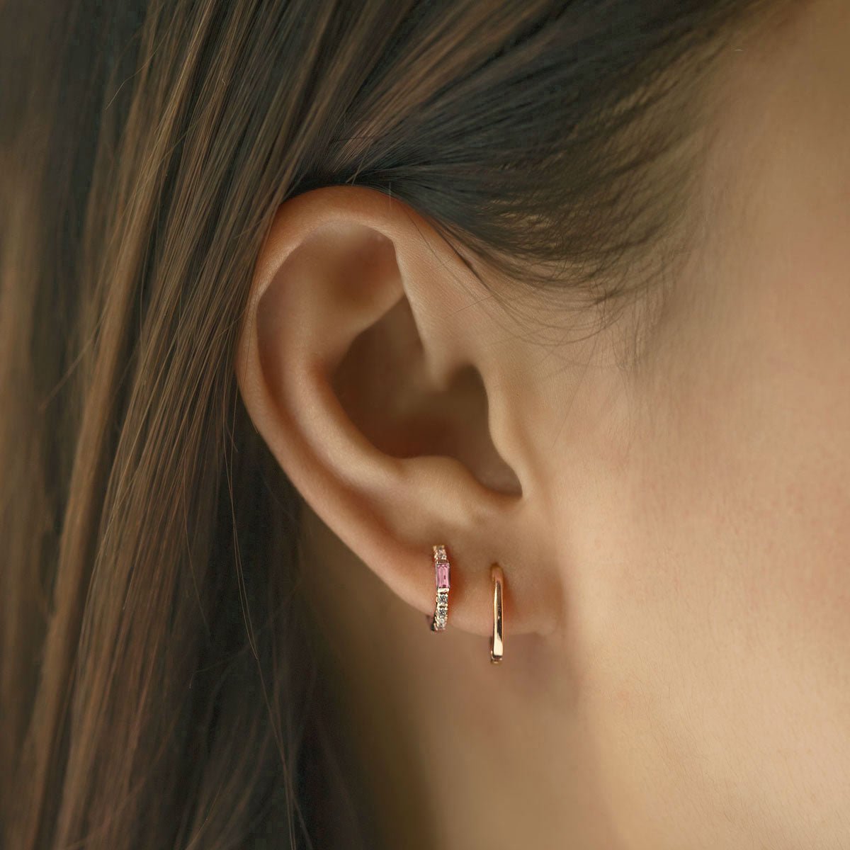 Close-up of woman's ear featuring Gold Vermeil Gemstone Baguette Huggie Earrings Pink and gold hoop.