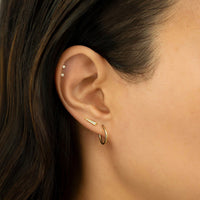 Close-up of woman's ear featuring Tiny 14K Gold Crystal Stud Earrings paired with stud earring