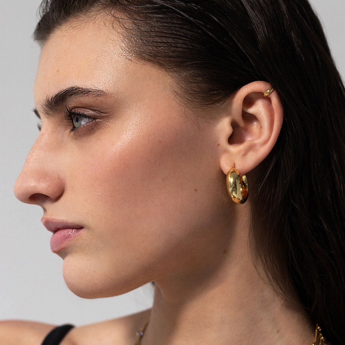 Model wearing chunky hoops and ear cuff crafted in gold vermeil from AMYO