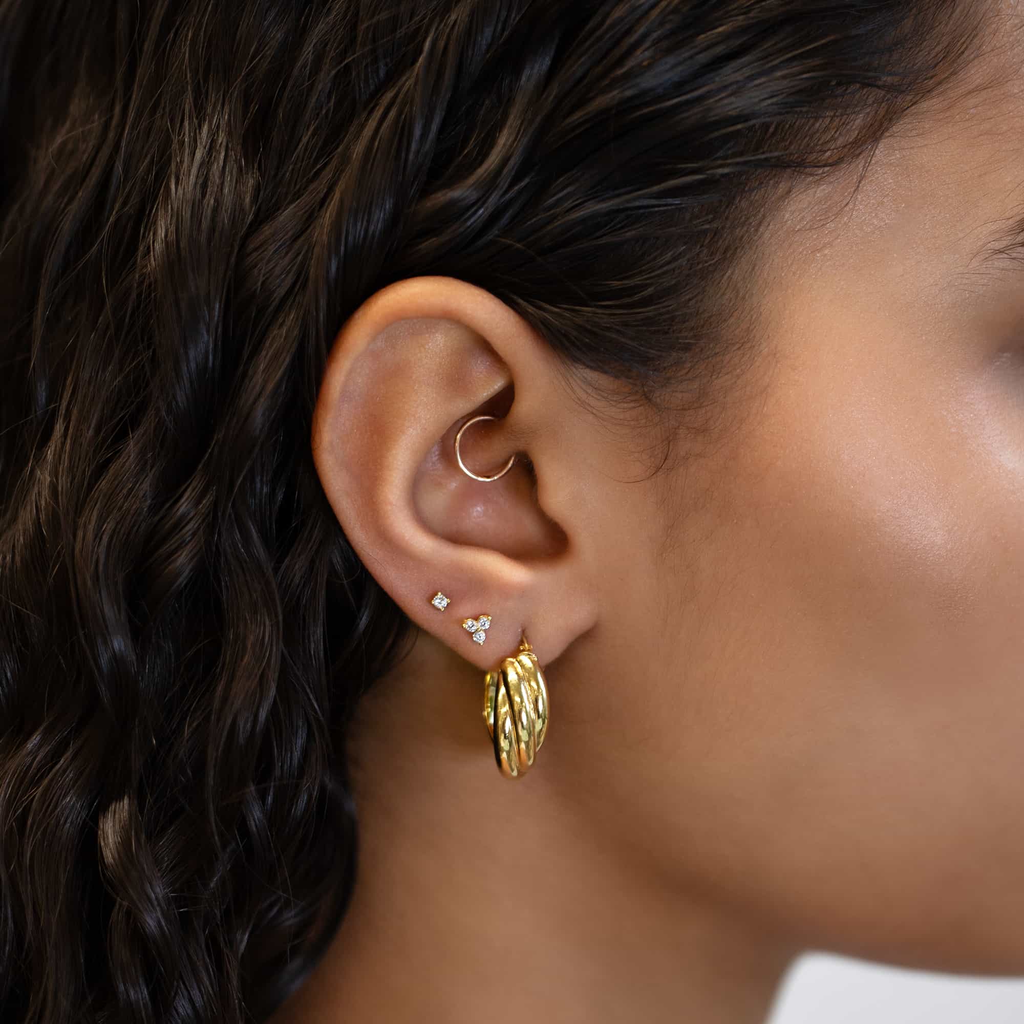 Close up of woman's ear featuring Gold Vermeil Birthstone Studs Set Cubic Zirconia and chunky twisted earring 