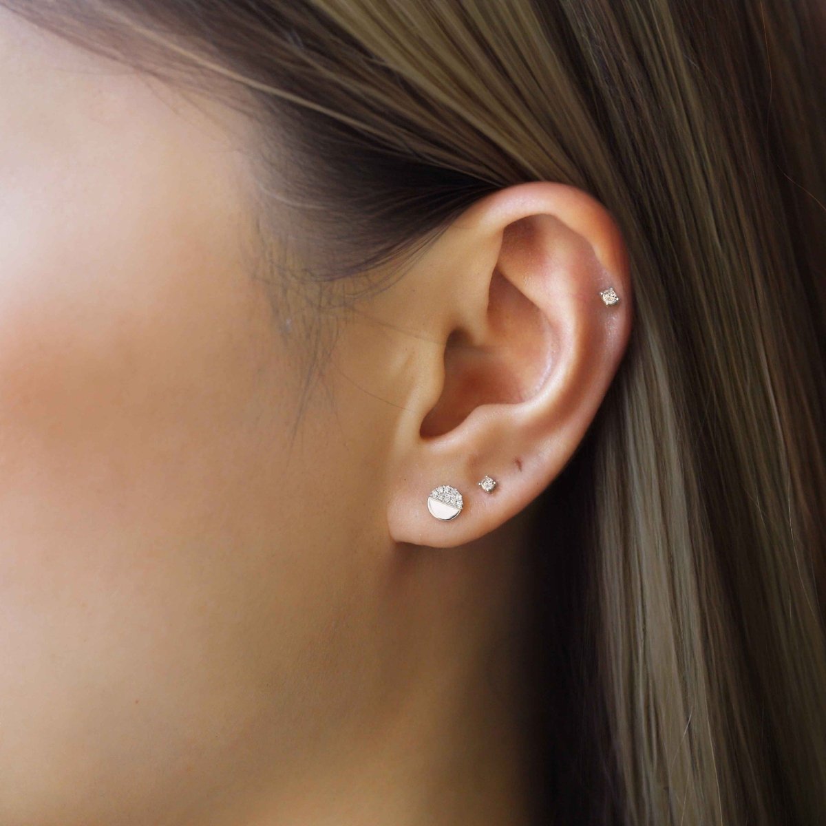 14K white gold half-disc stud with pave clear stones, shown on a model's lobe in an ear stack