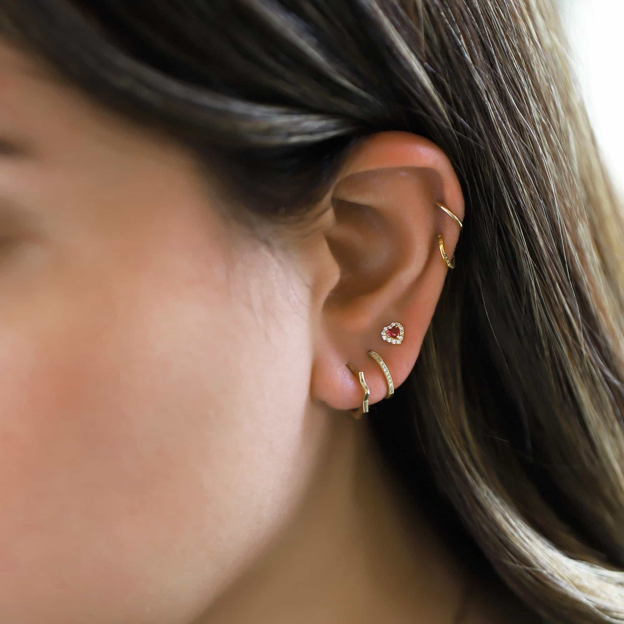 Close-up of woman's ear featuring 14K Gold Single Thin Pave Huggie and other 14K Gold Huggies. 