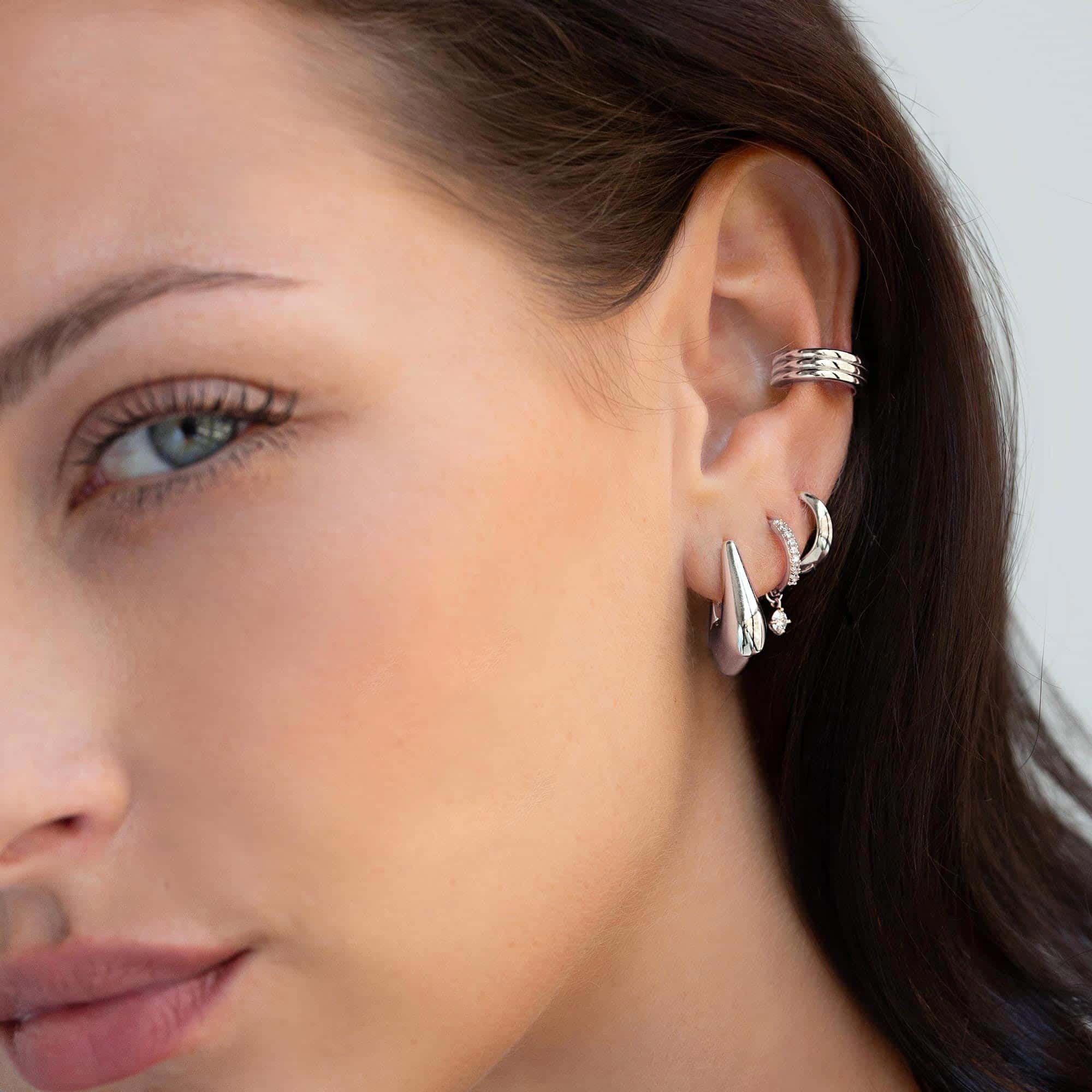 Close-up of sterling silver ear stack featuring bold silver hoops, huggies, cuff earrings. 