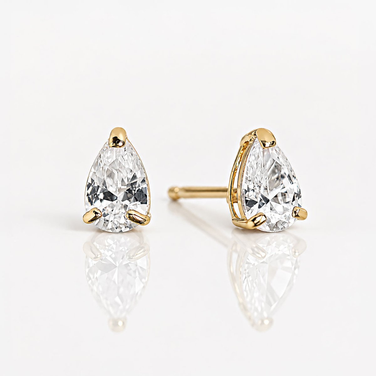 Pair of 14K gold pear-shaped stone studs on a white reflective surface, one post visible from the side