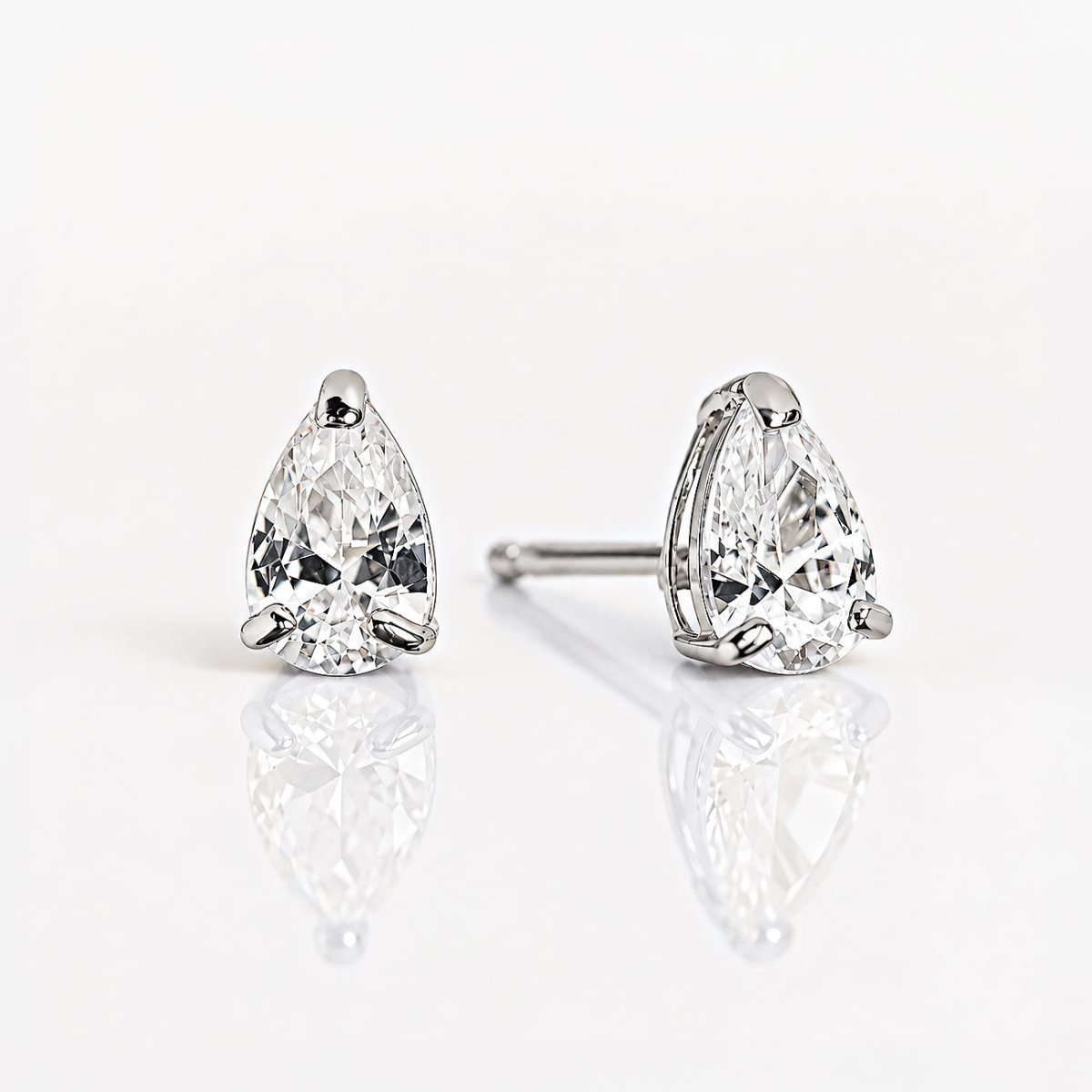 Pair of 14K white gold pear-shaped crystal studs on a reflective white surface, one post visible