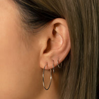 Close-up of woman's ear featuring 14K White Gold Thin Midi Hoops and Small Hoops 