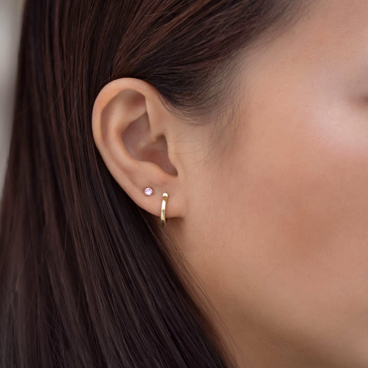 Close-up of woman's ear featuring 14K Solid Gold Birthstone Tiny Studs Pink and huggie earring