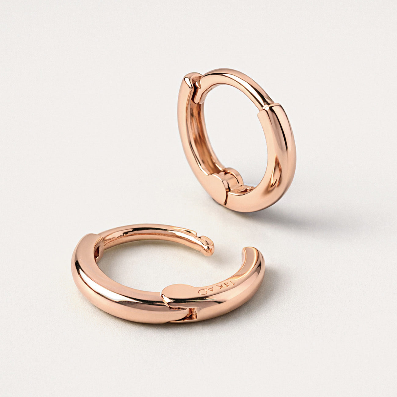Close up shot of AMYO'S Mini Huggie Hoops in 14K Rose Gold