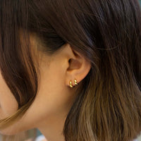 Close up of earrings featuring different sized 14K Solid Gold Boyfriend Huggies 