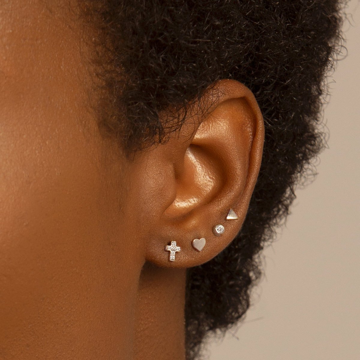 14K white gold pavé zirconia cross stud shown on a model's lobe in an ear stack