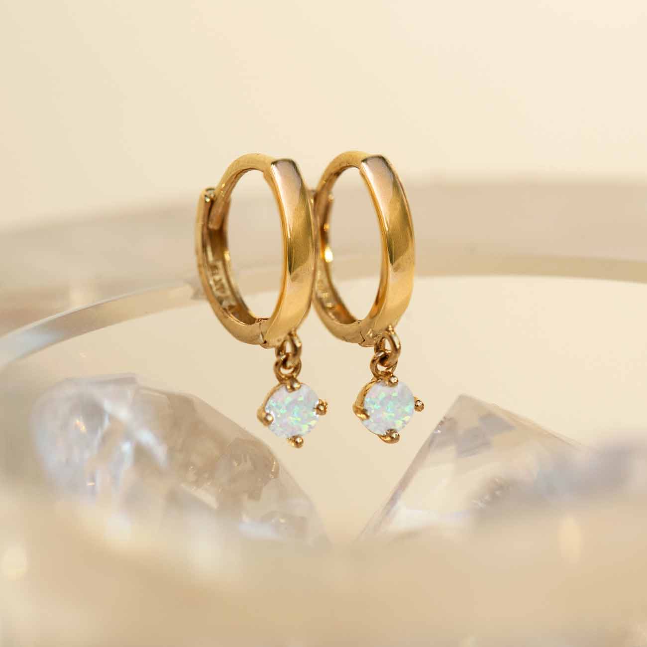 Close-up of earrings featuring 14K Gold Gemstone Dangle Huggies Opal