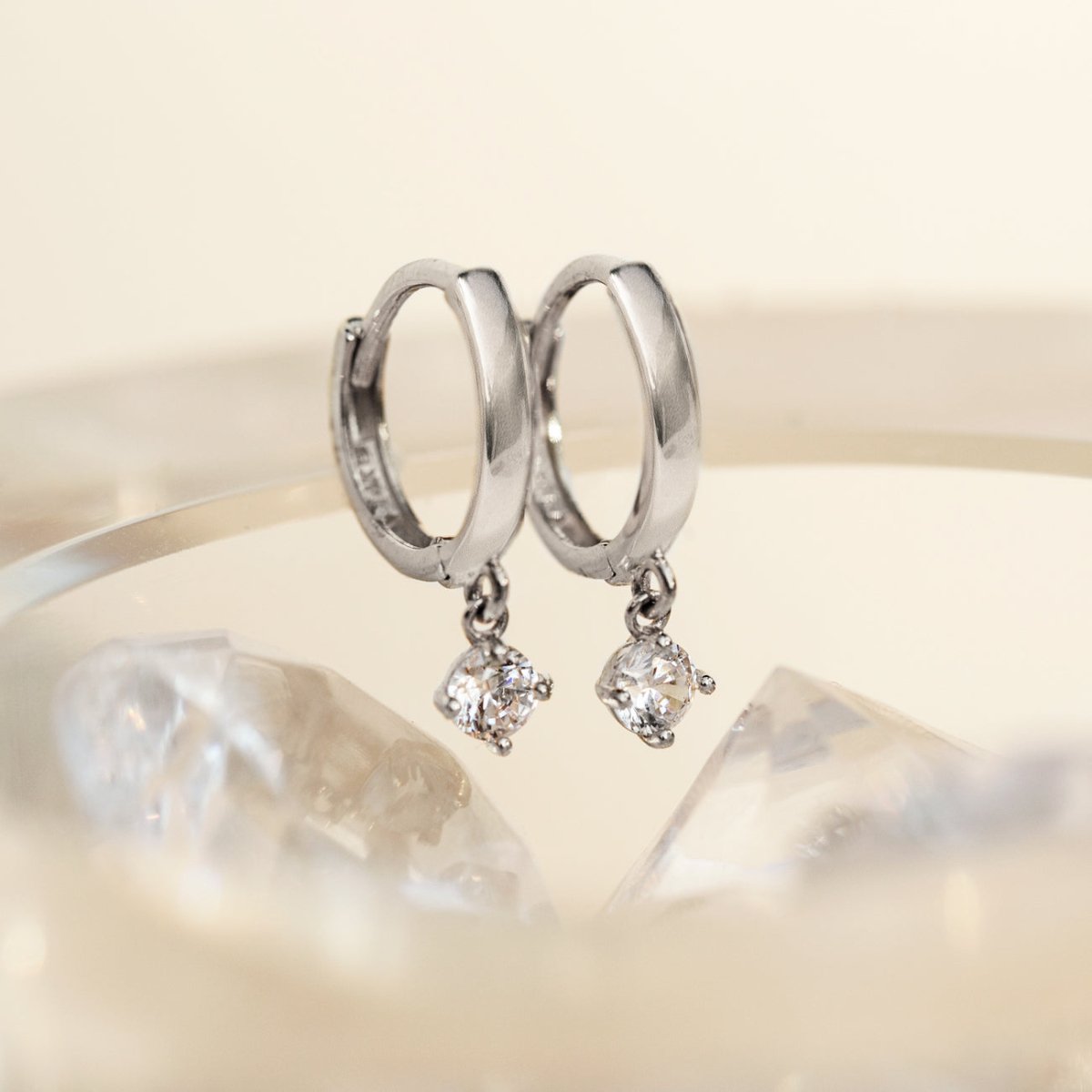 Close-up of earrings featuring 14K White Gold Pavé Dangle Huggie Earrings