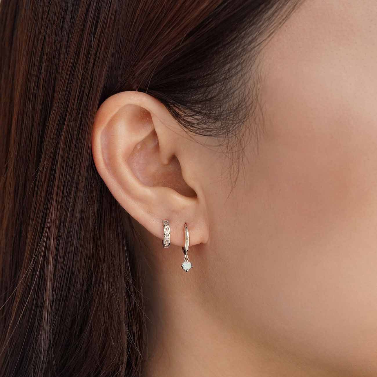 Close-up of woman's ear featuring 14K White Gold Gemstone Dangle Huggies Opal paired with 14K Pave Huggie Earring 