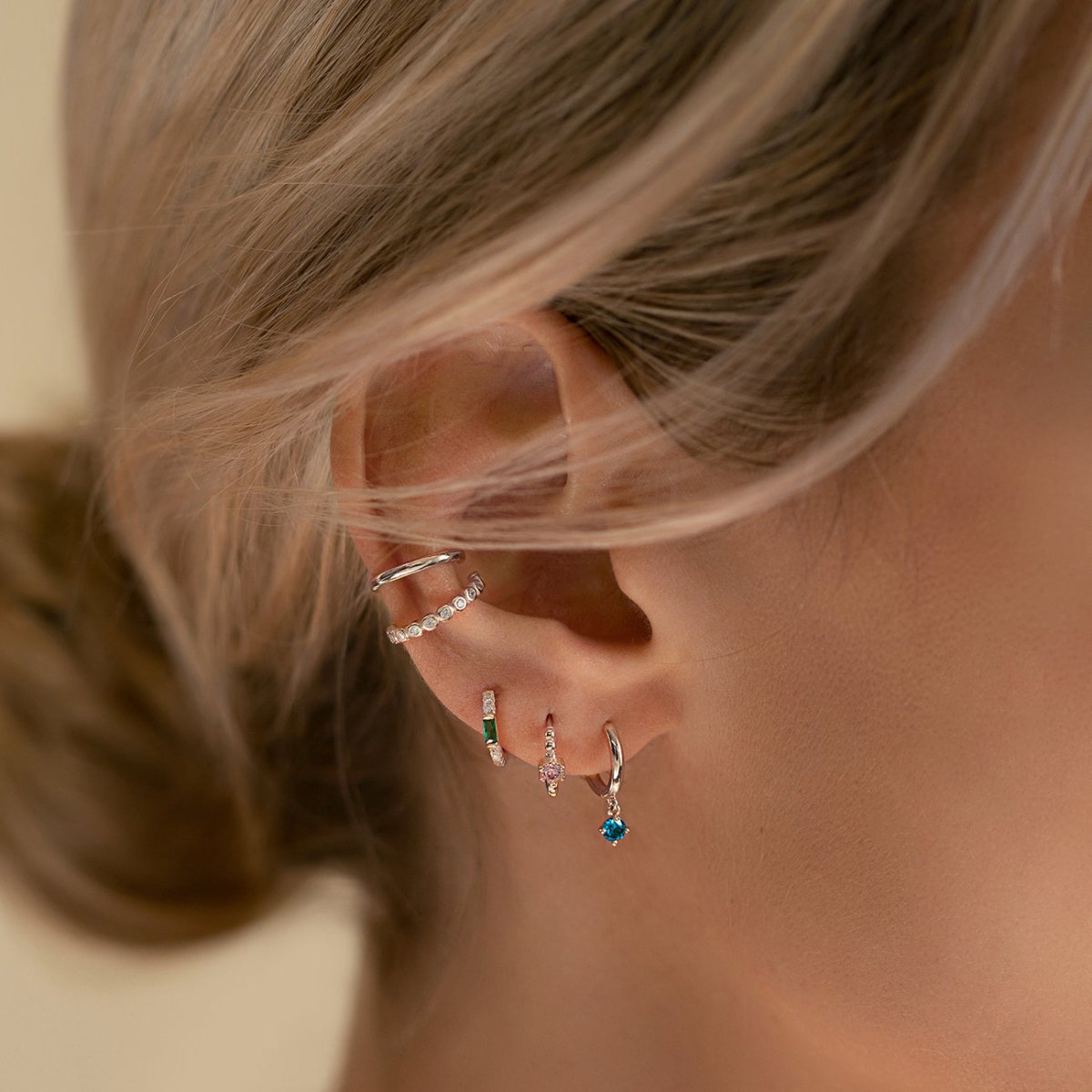 Close-up of woman's ear featuring Sterling Silver Gemstone Baguette Huggie Earrings Emerald and other gemstone earrings.