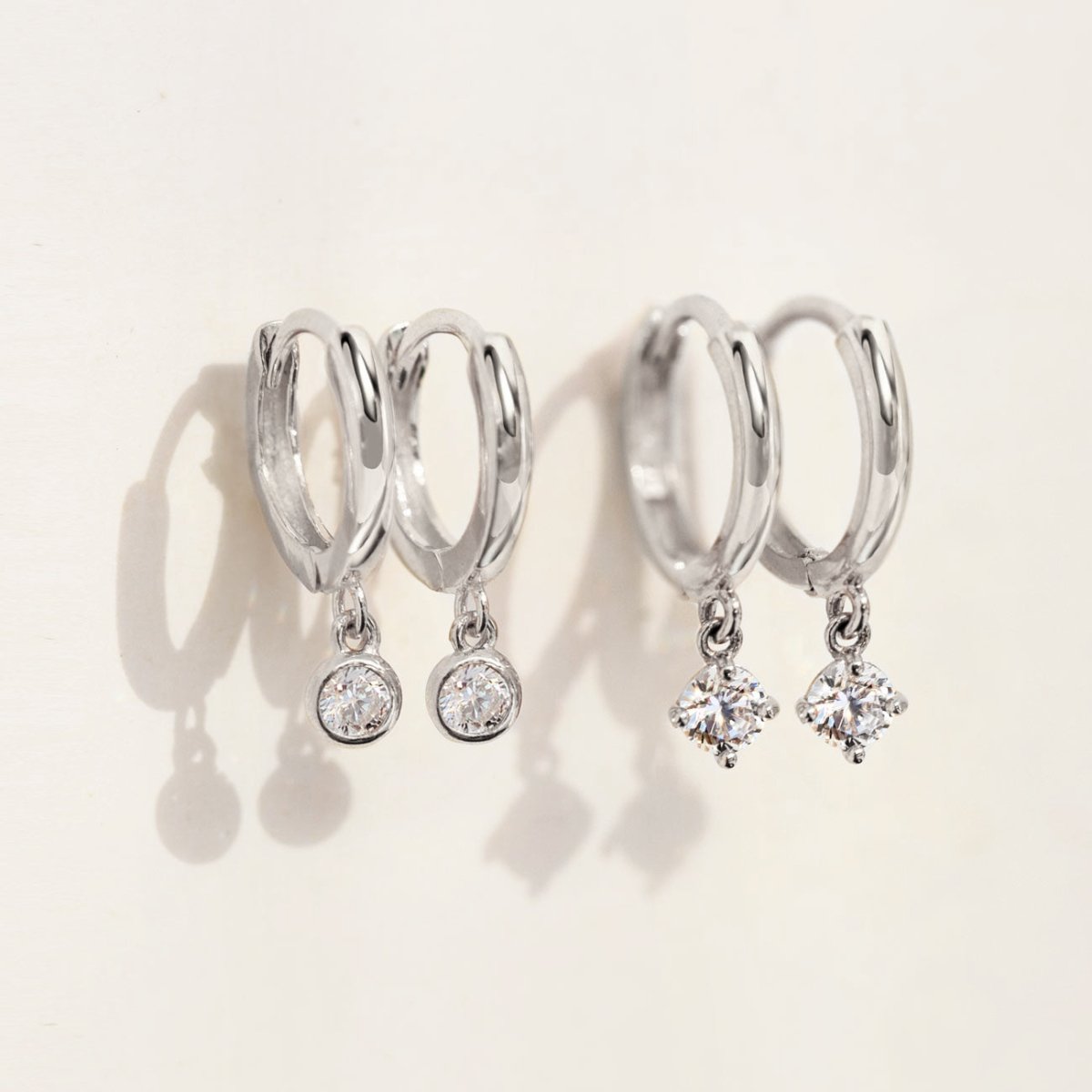 Close-up of earrings featuring 2 different 14K White Gold Pavé Dangle Huggie Earrings