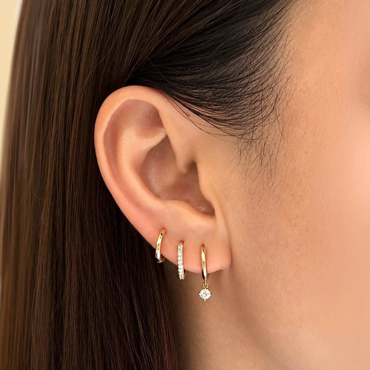 14K gold dangle moissanite pavé huggie hoops, and two other huggies shown on a model
