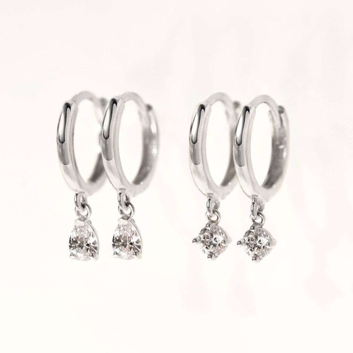 Close-up of earrings featuring 2 different 14K White Gold Pavé Dangle Huggie Earrings