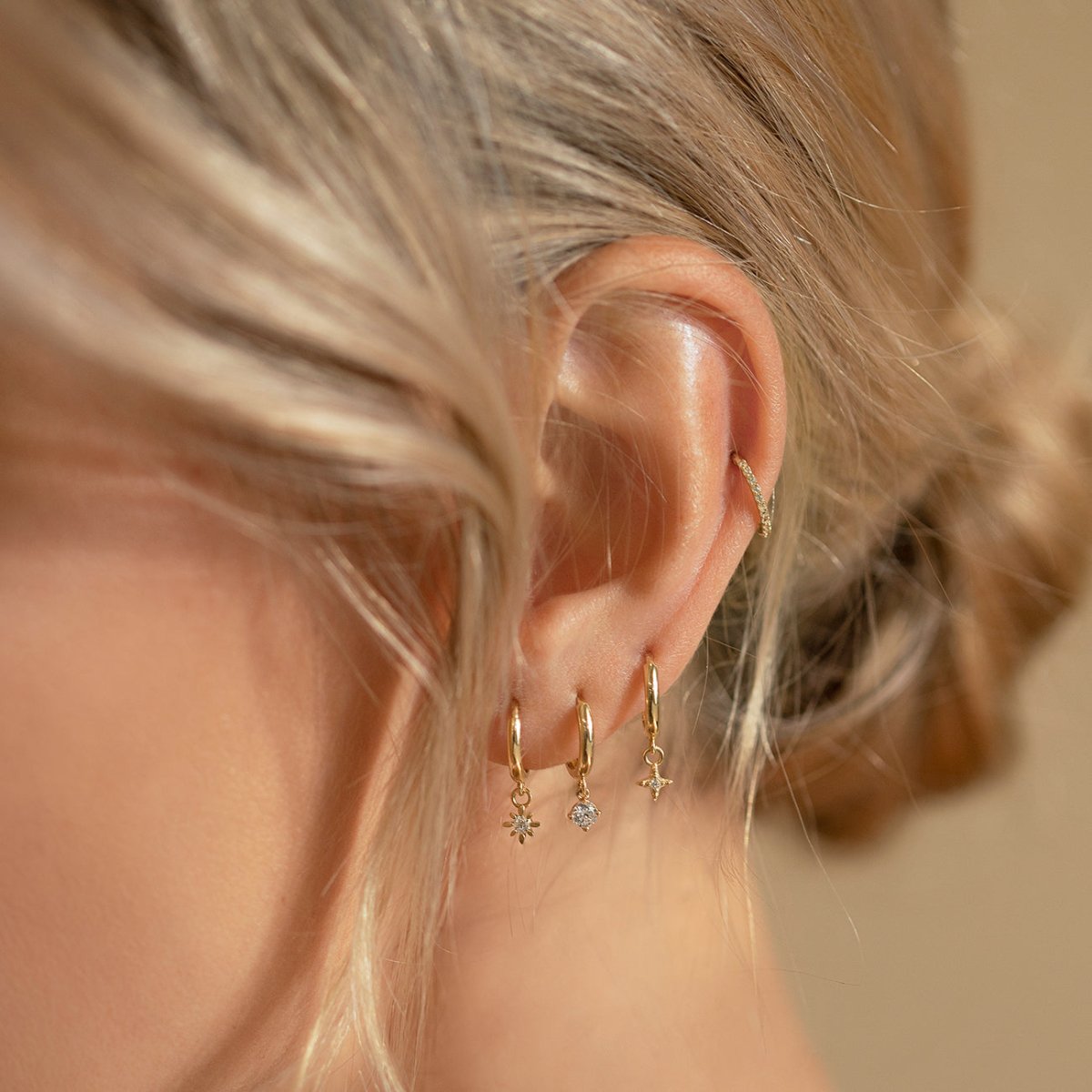 Close-up on woman's ear featuring 3 different 14K Gold Gemstone Dangle Huggies Moissanite