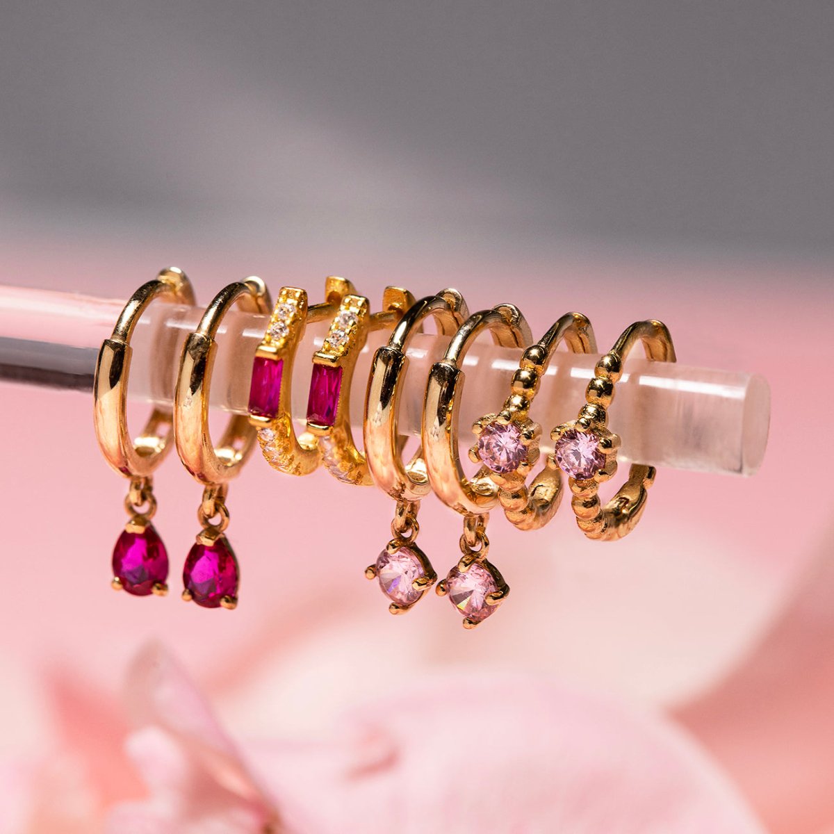 Close-up on earrings featuring 14K Gold Gemstone Dangle Huggies Pink + Ruby CZ Crystal 