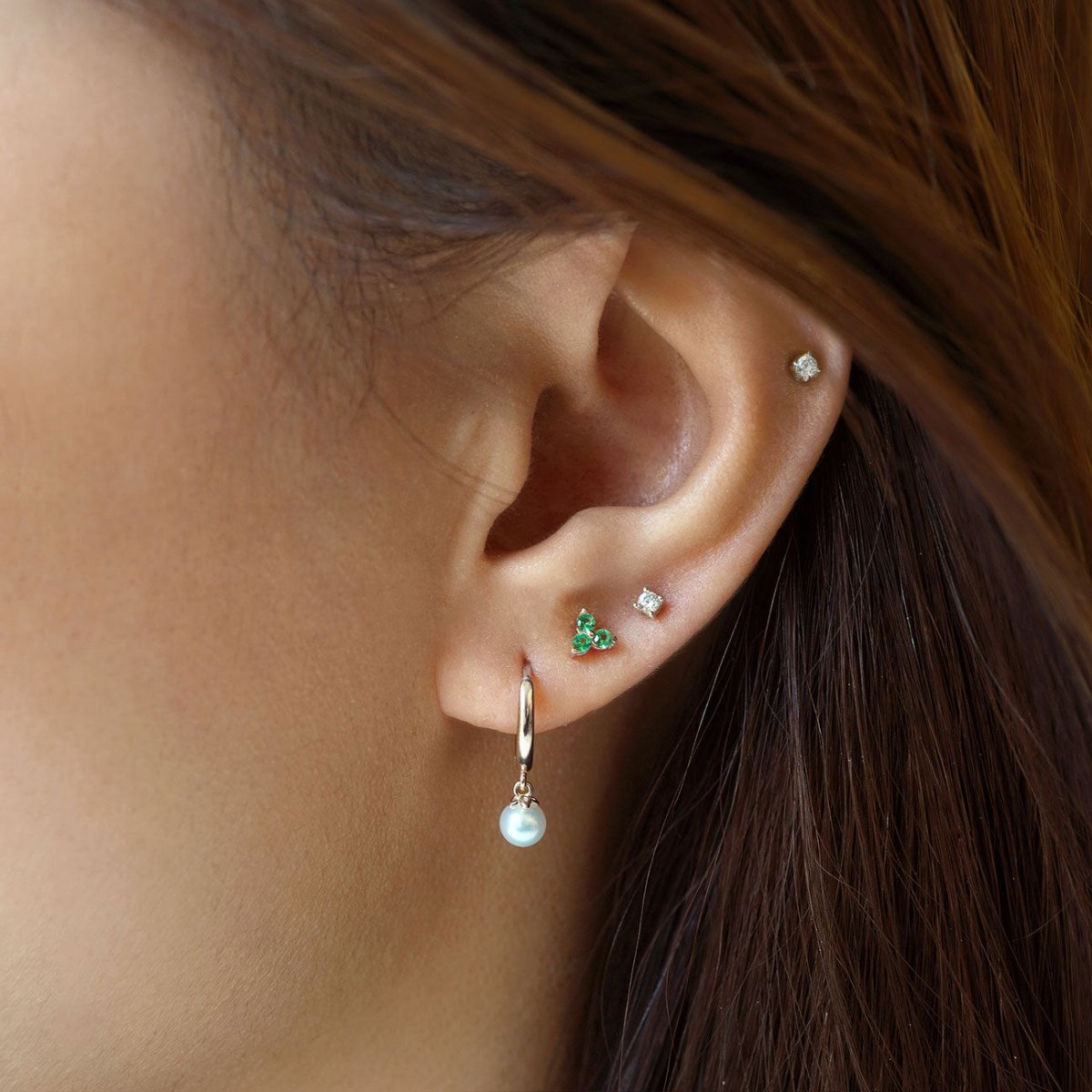 Close up of woman's ear featuring Sterling Silver Birthstone Studs Set Emerald and opal hoop earring 