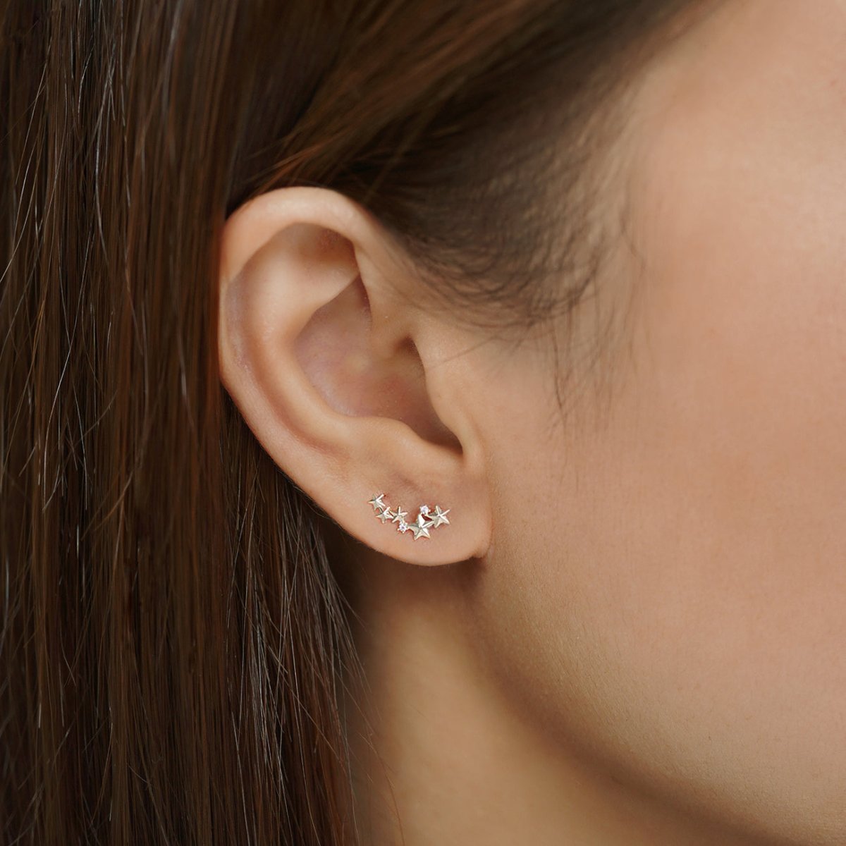 14K white gold star cluster stud with clear accents shown on a model's lobe