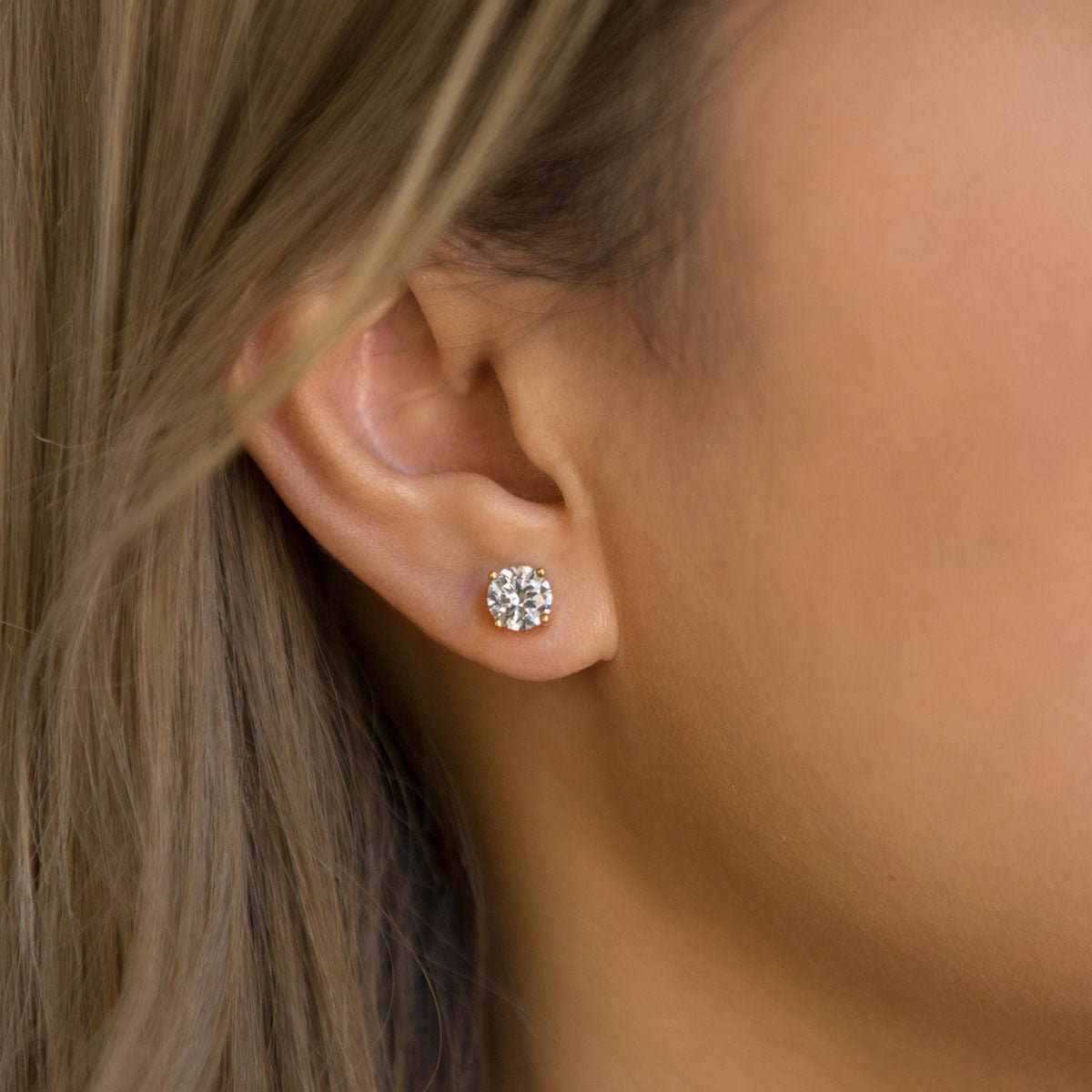 Close-up of woman's ear featuring 14K Gold White Sapphire Studs