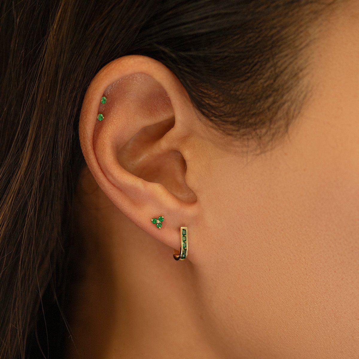 Close up of woman's ear featuring 14K Gold Gemstone Clover Studs Emerald CZ Crystal 