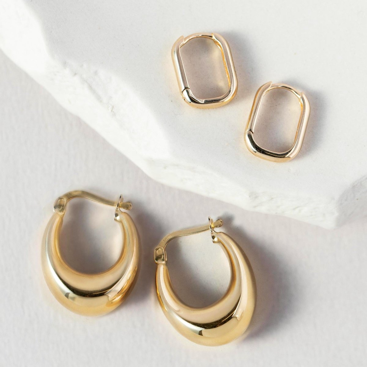 14K gold chunky U-shaped bubble hoop earrings shown on a model's ear