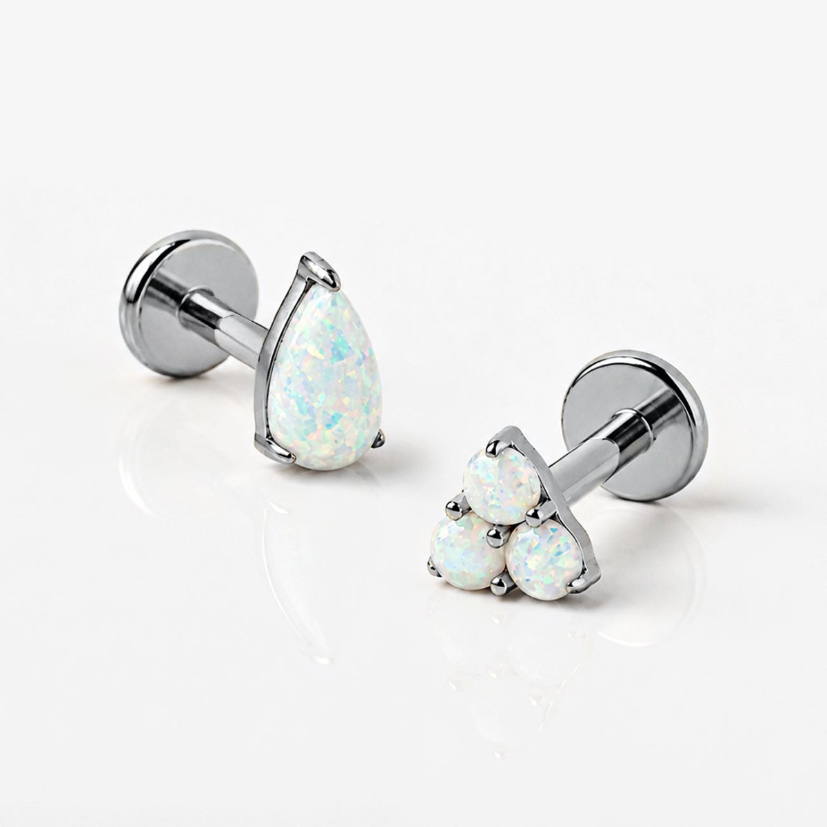Silver opal flat back earrings with pear and trinity designs on grey background.