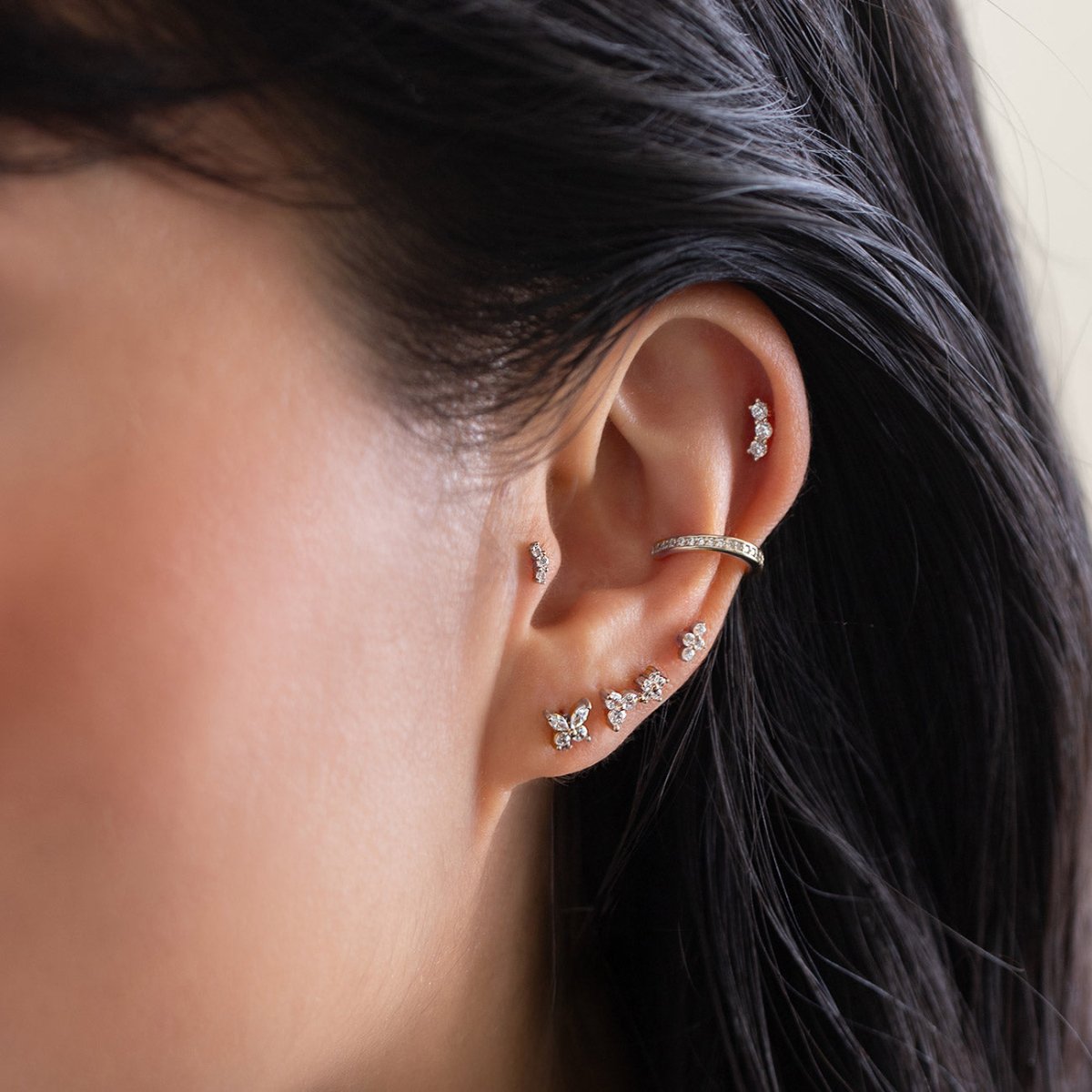 Close-up of an ear with multiple flat back stud earrings and ear cuff from AMYO