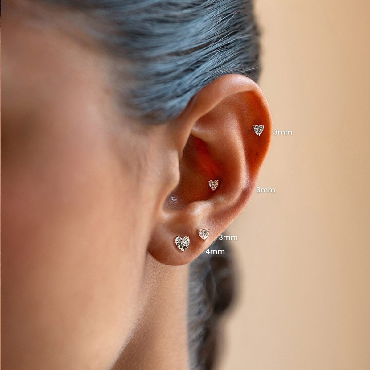 Four gold heart crystal flat back studs worn along a model's ear, labeled 3mm and 4mm