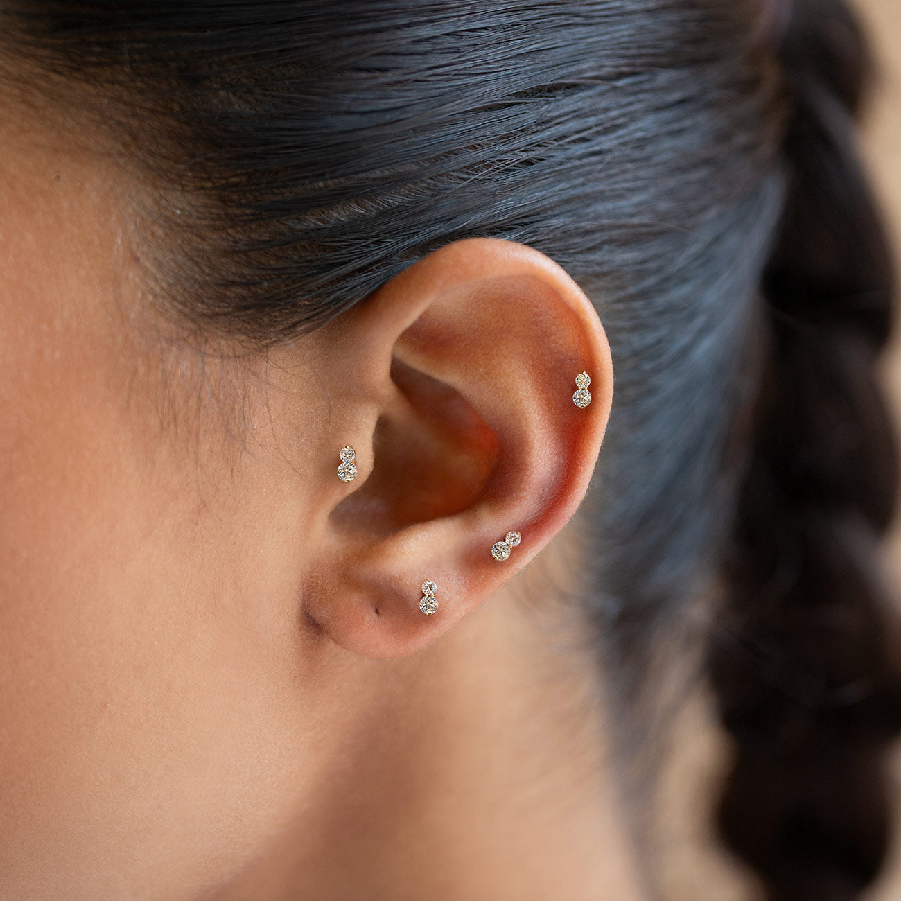 Gold pavé flat back stud earrings with two round crystals, shown on a model's ear |#Gemstone_White Zirconia