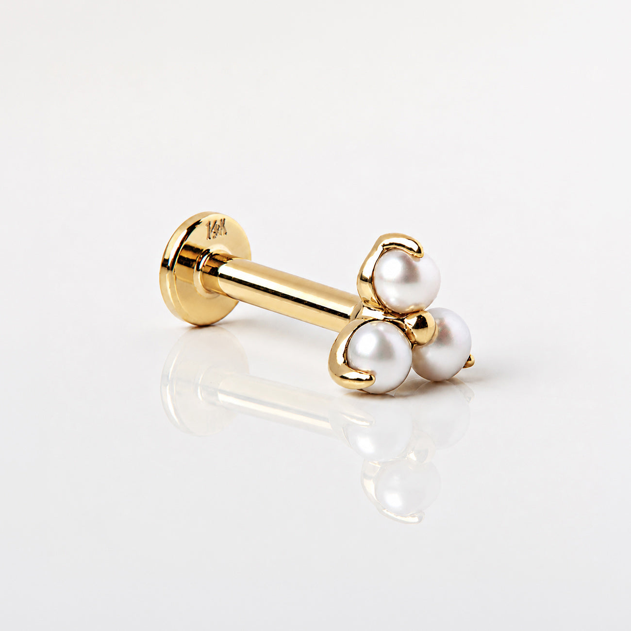 14K gold flat back stud with three small round white beads in a cluster, shown on a beige background