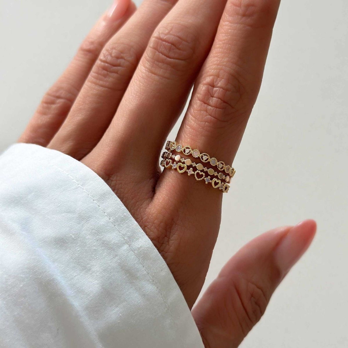 Gold vermeil heart and disc stacking rings with white zirconia, on a model's finger