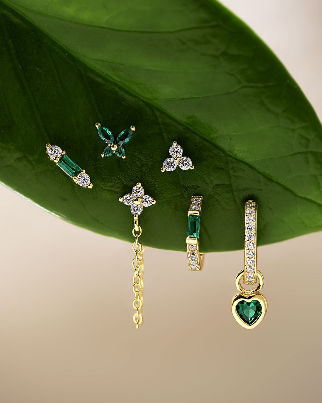 Green gemstone earrings with emerald green stones, crystal accents, gold huggies, studs and flat back earrings. Shop AMYO.