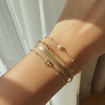 Close up video of wearing four bracelet styles from AMYO: Herringbone Bracelet, Heart Link Chain Bracelet, Pearl Bead Chain Bracelet, Crystal Bead Chain Bracelet