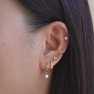 Model wearing 14k gold opal earrings, conch cartilage hoop and flat back studs.