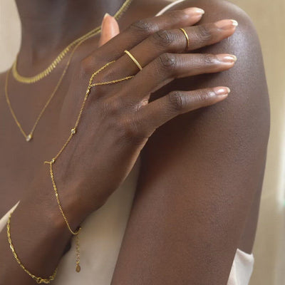 Woman wearing gold dainty crystal handchain and gold pave eternity ring