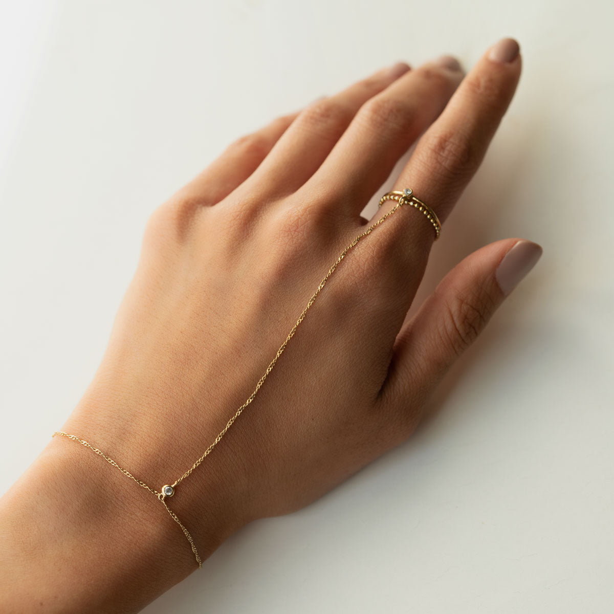 Hand wearing Gold Minimal Handchain and dainty bead chain ring