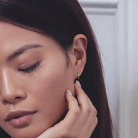 Model wearing rose gold tiny cross huggies with conch earring