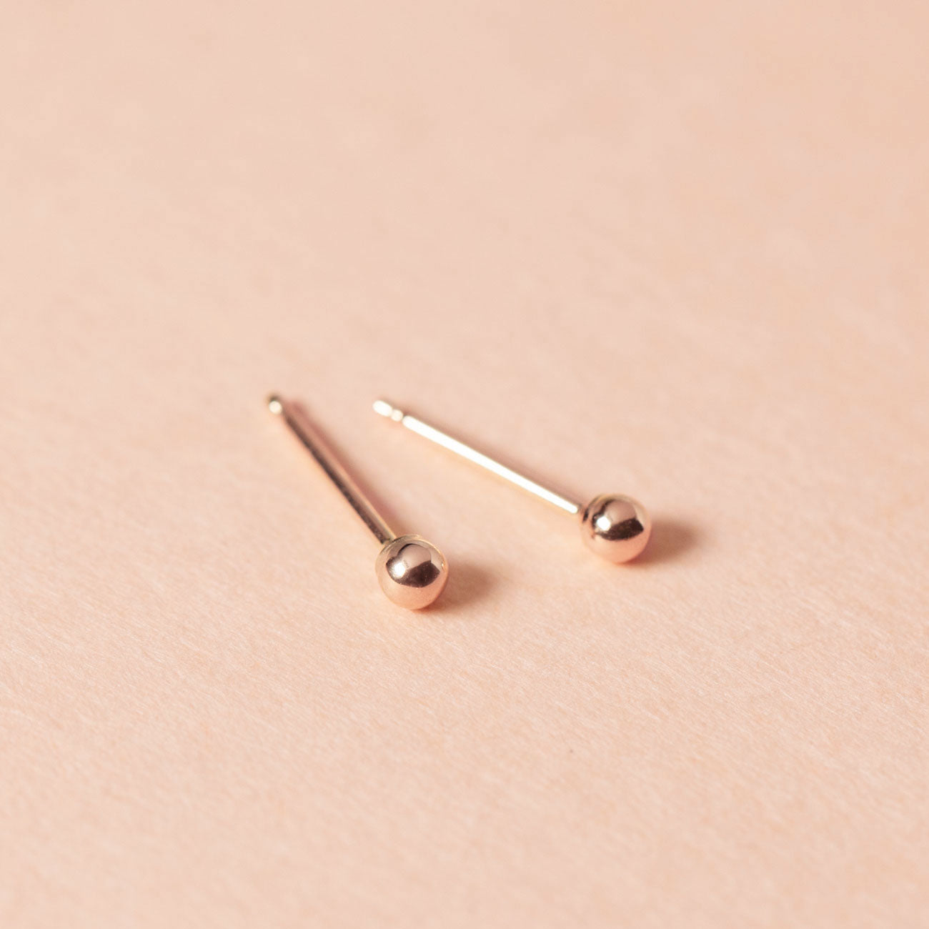 Close-up of earring featuring Tiny 14K Rose Gold Sphere Studs