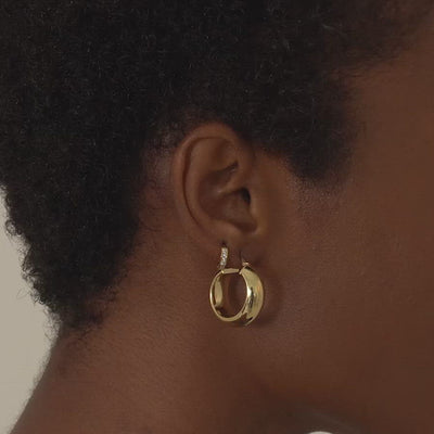 Close-up of woman's ear featuring 14K Gold Single Pave Huggie CZ Crystal and Gold Vermeil Chunky Hoops. 