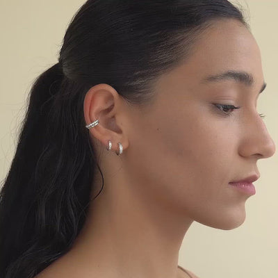 Woman wearing 14k white gold single pave huggies and sterling silver eternity ear cuff